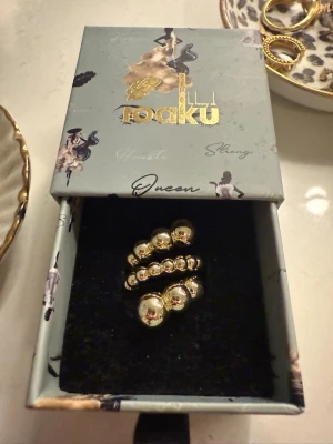 Guldfärgad pärlring från Ioaku - Säljer en snygg guldfärgad ring från Ioaku med dubbla rader av glänsande pärlliknande kulor. Ringen har en modern och trendig design som verkligen sticker ut. Perfekt accessoar för att lyfta din stil. Ringen är adjustable.💗✨