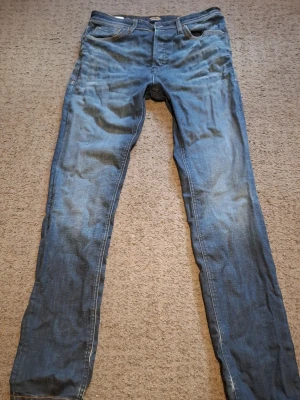 Jack & Jones jeans - Säljer ett par blåa Jack & Jones med passform slim straight och klassisk femficksdesign, Storlek 30W 34L. Jeansen har snygga slitningar och kontrastsömmar. Perfekta för dig som gillar en tidlös och enkel stil. Skrive vid frågor.