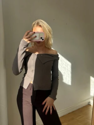 Grå ribbad offshoulder topp💖✨ - Trendig grå ribbad topp med offshoulder-design och långa ärmar. Toppen har knappar framtill och en unik krage som ger en cool twist. Perfekt för dig som gillar en stilren men ändå edgy look.