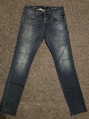 Replay anbass jeans - Snygga blå slim fit jeans från replay femficksmodell med vita kontrastsömmar och läderpatch bak i midjan. Perfekta för en avslappnad och trendig look.