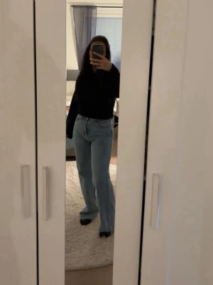 Ljusblå raka jeans med hög midja - Säljer ett par ljusblå jeans med hög midja och raka ben. Jeansen har klassisk femficksdesign och är tillverkade i ett mjukt denimtyg. Perfekta för en avslappnad och trendig look.