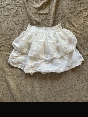 Vit volangkjol med spetsdetaljer - Söt vit kortkjol med dubbla volanger och fina spetsdetaljer längs kanterna. är I strl XS oh priset kan diskuteras vid snabbt köp. Buda inte om du inte vill köpa!💕