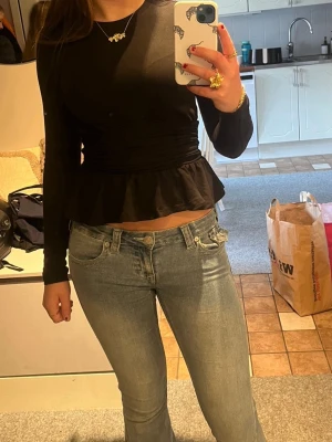 Svart långärmad topp med volang från Gina tricot - Trendig svart topp med långa ärmar och volang nedtill i storlek xs. Säljs eftersom jag inte använder. 