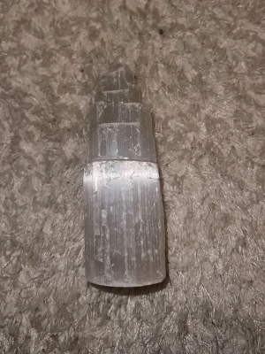 Selenittorn kristallvit dekoration - Säljer ett selenittorn i kristallvit färg, format som ett torn med flera nivåer. Materialet är selenit, vilket ger en skimrande och genomskinlig look. Perfekt som dekoration eller för dig som gillar kristaller och mineraler.