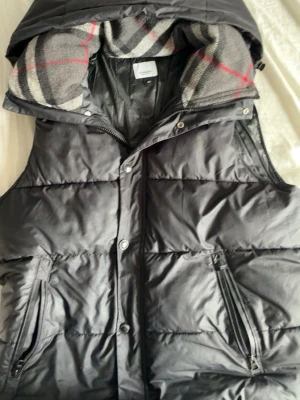 Svart burberry Jacka/väst - Säljer min burberry jacka/väst då den är förliten. Den har en liten skada på dragkedjan men inget som syns. Storlek S men passar även M