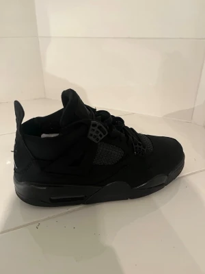 Svarta Air Jordan 4 black retro sneakers - Säljer ett par helsvarta Air Jordan 4 retro sneakers med meshpaneler och detaljer i plast. Skorna har en chunky sula och klassisk siluett med snörning och pull tab bak. Materialet är en mix av mocka och textil för en clean och sportig look. Använda 3-4 gånger köpt för 2500 säljer för 1800 pris kan gå ner lite