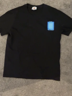 Svart Casa Blanca t-shirt - Snygg svart t-shirt från Casa Blanca med en liten blå detalj och logga på bröstet. Klassisk rund hals och korta ärmar. Perfekt basplagg med stilren design och skön passform i mjuk bomull.