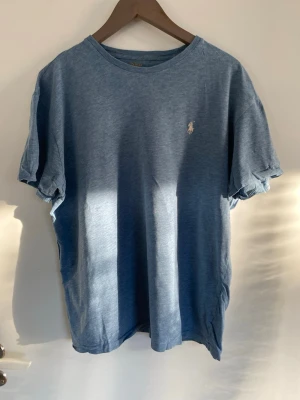 Blå tisha  - Ljusblå Ralph lauren T-shirt med gul text i nacken och vitt tryck på bröstet.
