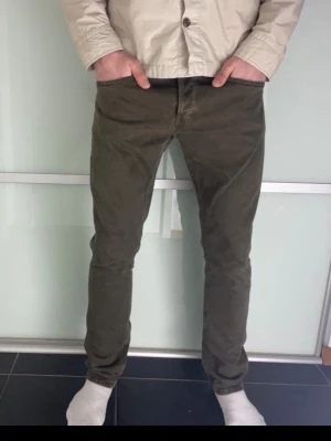 Dondup jeans - Säljer ett par slim fit jeans i olivgrönt med klassisk femficksmodell och normal midja. Jeansen har raka ben och är tillverkade i ett mjukt bomullsmaterial med lite stretch för extra komfort. Perfekta för en avslappnad och snygg stil.