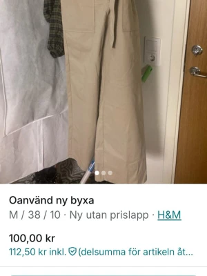 Beige vida leggings från H&M - Säljer ett par beige leggings från H&M med hög midja och breda ben. Byxorna har stora fickor framtill och ett matchande knytband i midjan. Perfekta för en avslappnad och trendig look.