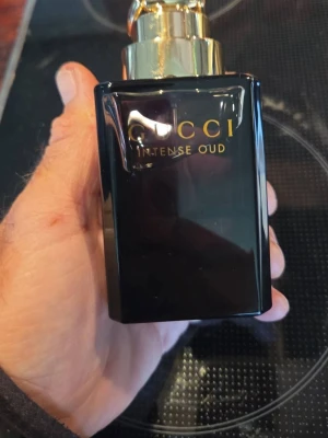 Gucci Intense Oud parfym 90ml - Gucci Intense Oud parfym i en elegant svart glasflaska med guldfärgat lock. Flaskan har en lyxig och stilren design med guldtext på framsidan. Doften är orientalisk och exklusiv, perfekt för dig som gillar djupa och intensiva parfymer. Provsprayad  ej box 