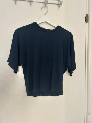Mörkblå loose t-shirt - En enkel mörkblå t-shirt med loose passform och korta ärmar. T-shirten har rund halsringning och är tillverkad i ett mjukt material som känns skönt mot huden. Perfekt för en avslappnad stil.
