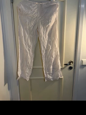 Vita vida linnebyxor - Säljer ett par vita linnebyxor med avslappnad passform och raka ben. Byxorna har resår i midjan för extra komfort och är tillverkade i ett lätt och luftigt linnematerial. Perfekta för en chill och stilren look.