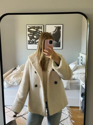 Maison Lener kappa med luva  - Säljer en vit, fluffig kappa med dubbelknäppning. Jackan har en stor mysig luva och är i ett mjukt, teddy-liknande material 🤍 Gjord av Alpacka och Ull. Nypris ligger runt 8 000 - 12 000 kr 