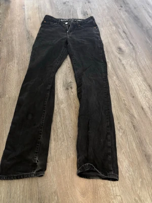 Svarta raka jeans  - Säljer ett par svarta jeans med rak passform och klassisk femficksdesign. Jeansen har normal midja och dragkedja med knapp. Perfekta för en avslappnad och stilren look.