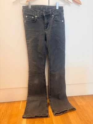 Grå bootcut jeans med rå kant - Säljer ett par grå bootcut jeans med rå, fransig kant nedtill. Jeansen har klassisk femficksmodell, normalhög midja och är tillverkade i stretchigt denimtyg. Perfekta för dig som gillar en avslappnad men trendig look.