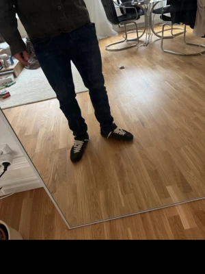 Mörkblå raka jeans - Säljer ett par mörkblå jeans med rak passform och klassisk femficksdesign. Jeansen har normal midja och är tillverkade i denim. Perfekta för en avslappnad och stilren look.