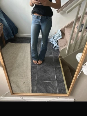 Blå bootcut jeans med låg midja - Säljer ett par klassiska blå bootcut jeans med låg midja och fem fickor. Jeansen har en snygg tvätt och sitter tajt över låren för att sedan bli vidare nedtill. Perfekta för dig som gillar en retro och avslappnad stil. Jag är 167