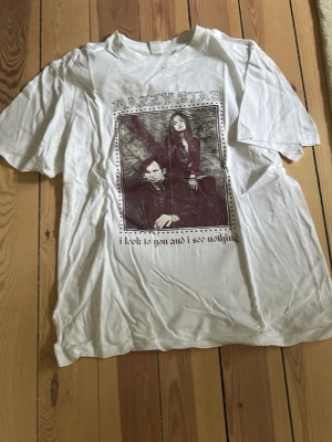 Vit Mazzy Star band t-shirt - Vit t-shirt med tryck av bandet Mazzy Star på framsidan och texten 'i look to you and i see nothing'. Klassisk passform och rund hals. Perfekt för dig som gillar bandmerch och vill ha en avslappnad stil.