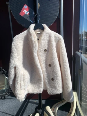 Vit teddyjacka med knappar - Vit teddyjacka med tre knappar framtill och hög krage. Knappt använd