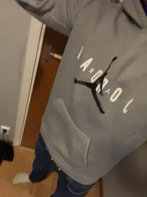 Grå Jordan hoodie med logga - Säljer en grå hoodie från Jordan med den klassiska Jumpman-loggan och vit text på bröstet. Hoodien har lång ärm, stor framficka och en bekväm passform. Perfekt för dig som gillar sportiga och stilrena plagg.