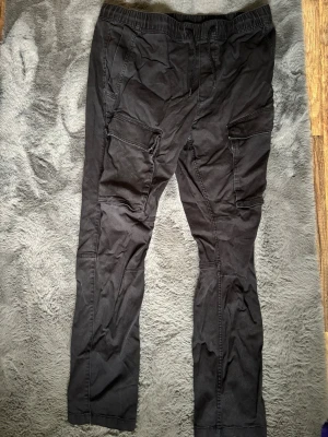 Svarta cargobyxor från H&M Skinny Fit - Säljer ett par svarta cargobyxor från H&M i modellen Skinny Fit. Byxorna har flera praktiska fickor på sidorna och är tillverkade i bomull med lite stretch. Perfekta för en avslappnad och trendig look.