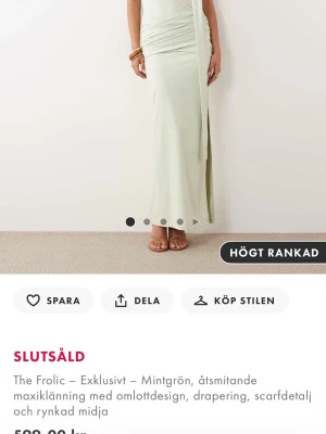 Mintgrön omlottklänning The Frolic - Säljer en mintgrön långklänning från The Frolic med omlottdesign, drapering och scarfdetalj. Klänningen har åtsmitande passform och rynkad midja som ger en snygg siluett. Perfekt för dig som vill ha något elegant och trendigt.