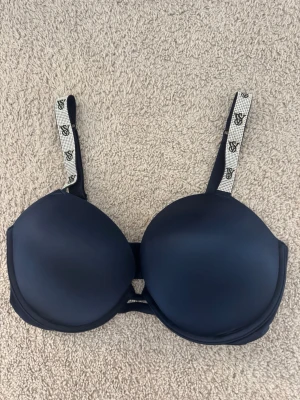 Mörkblå push-up bombshell bh VS  - Snygg mörkblå push-up bh från Victoria's Secret med vadderade kupor och justerbara axelband med logotypdetaljer. Bh:n har släta kupor och elastiskt material för skön passform. 