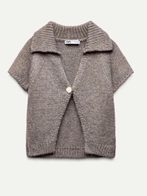 Kortärmad stickad kofta från Zara - Kortärmad stickad kofta i mjuk, beige ullmix från Zara. Koftan har en bred krage, en knapp framtill och ribbade kanter. Perfekt att bära över ett linne eller t-shirt för en avslappnad och trendig look.