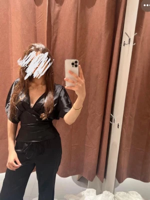 Svart satin jumpsuit med omlottopp - Tröja från ginatrcot passar mig som S men är L efter som man kan fixa storlek bakifrån byxor är från Zara och är i storlek S säljer båda som en sätt 