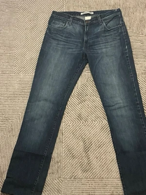 Mörkblå raka jeans från J.Lindeberg - Storlek 34/34            Snygga mörkblå jeans från J.Lindeberg med raka ben och klassisk femficksmodell. Jeansen har diskreta slitningar och en metallogo på myntfickan. Tillverkade i denim med en autentisk tvättad look.
