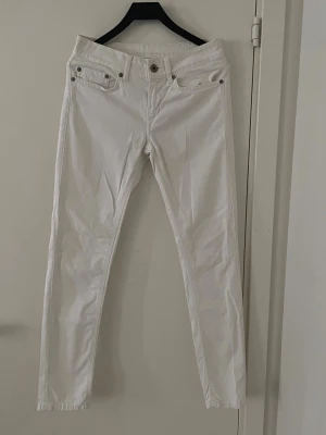 Dondup vita jeans - Tjenare säljer ett par snygga vita slim jeans med låg midja och klassiska fem fickor. Dessa Dondup jeans har smala ben och silverfärgade nitar vid fickorna. Perfekta för en clean och fräsch look. Materialet känns mjukt och stretchigt, vilket gör dem bekväma att bära hela dagen. Passar otroligt bra till alla tillställningar😁skicket är 9,5/10 och storlek 26 som lär passa ungefär 160-170 möjligtvis! Hör av dig vid mer frågor eller funderingar🕺Mvh Ga🤩