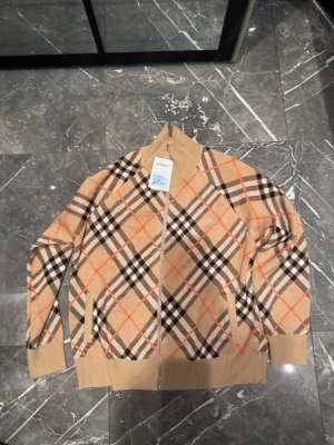 Burberry stickad tröja Strl L  - Helt ny Burberry stickad tröja med prislappar kvar. Aldrig använd. Klassisk och stilren design som passar både till vardags och finare tillfällen. Storlek L, men modellen är ganska stor i passformen och sitter mer som en XL.