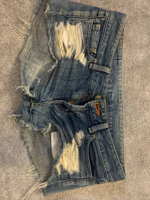 Blå slitna jeansshorts med fransar - Säljer ett par jeans shorts som är riktigt snygga. Säljer dom för dom är försmå tyvärr😥 Jätte fina till sommarn. Dom är i ett bra skick, använt några gånger men ingen fläck eller något som gått sönder på dom!  Dom är ganska små i storlek och är väldigt lågmidjade som jag älskar me dom.