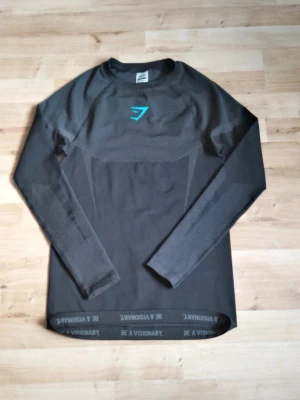 Gymshark onyx v5  - Gymshark Onyx V5 Seamless Long Sleeve i svart färg och storlek S. Garanterat ÄKTA  Tillverkad i ett sömlöst, ventilerande material som ger hög komfort under träning. Modern passform med Gymshark-logga på bröstet och "Be A Visionary"-detalj i nederkant. Mycket gott skick utan anmärkningar.