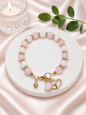 Armband med rosenkvarts  - Armband med rosenkvarts, svagt ljusrosa matta och ljusrosa klara. Guldiga mellandelar och olika hängen i rostfritt stål. Ett stilfullt armband som är lika vacker till sommarklänningen som till jobbmötet.
