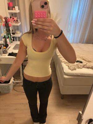 Gul tight t-shirt med rund ringning - Snygg gul t-shirt med tight passform och djup rund ringning. Kortärmad modell i mjukt stretchigt material, perfekt till jeans eller kjol. Enkel och stilren design utan tryck eller mönster.