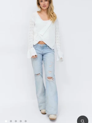 Ljusblå slitna bootcut jeans - Säljer ett par ljusblå bootcut jeans med slitningar och hål på framsidan. Från gina tricots 14+ avdelning. Jeansen har låg midja och klassisk femficksdesign. Perfekta för en avslappnad och trendig look. Materialet är denim i bomull. Använda fåtal gånger. 