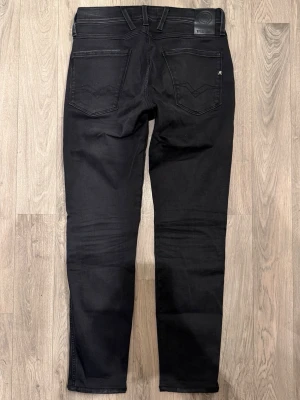 Replay Anbass Hyperflex Svarta Jeans W29/L34 Slim Fit - Replay Anbass Hyperflex svarta jeans i stretchigt och bekvämt material, slim fit modell som sitter bra och funkar till allt, storlek W29/L34, midja 38 cm, ytterbenslängd 97 cm, benöppning 14,5 cm, modellen är 185cm & väger 65kg, i fint skick.