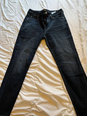 Mörkblå Lee Scarlett High jeans - Snygga mörkblå jeans från Lee, modell Scarlett High med hög midja och smal passform. Klassisk femficksdesign och stretchigt material för extra komfort. Perfekta för dig som gillar en tidlös och stilren look.
