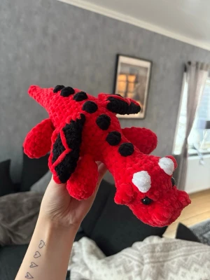 Virkad röd drake 🐉  - Virkad röd & svart drake – handgjord & unik 🐉🖤❤️ En charmig och mjuk virkad drake, perfekt som present, inredningsdetalj eller gosedjur för större barn • Draken är stadig men samtidigt mjuk och kramvänlig, och passar lika bra i barnrummet som på hyllan eller sängen 🐉OBS! ⚠️ Innehåller säkerhetsögon – rekommenderas ej till barn under 3 år.
