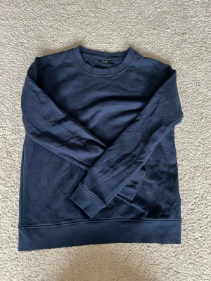 Mörkblå sweatshirt från LMTD - En stilren mörkblå sweatshirt från LMTD i storlek M, passar perfekt för dig som gillar en enkel och clean look. Tröjan har rund halsringning, långa ärmar och ribbade muddar vid ärmslut och nederkant. Skön och mjuk bomullskänsla.