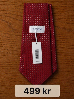 Röd slips med geometriskt mönster Eton - Snygg röd slips från Eton med små vita geometriska mönster. Tillverkad i ett exklusivt tyg som ger en lyxig känsla. Perfekt accessoar för att lyfta din outfit med en färgklick och stilren design.Nypris ca 1000–1500 kr/st – säljes till riktigt bra pris. Paketpris 1600kr.