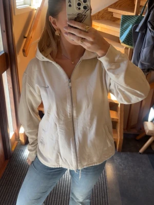 Beige hoodie med dragkedja från Nike - Beige hoodie från Nike med dragkedja och justerbar nedtill. Säljs ej längre, storlek S men oversized🌸