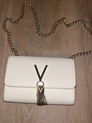 Väska - Valentino väska, köpt online på zalando, kvitto/leverans finns kvar köpt 2024, använd fåtal gånger , har nån liten svart fläck inget jätte synligt på baksidan, ren och fin vanligtvis, silver och vit. Har dock inte påsen kvar/förpackning! ⭐️Den är ÄKTA! Den är liten/axelremsväska! Köptes för 722kr online! 