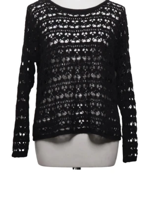 Svart virkad stickad tröja - Snygg svart stickad tröja med virkat mönster och långa ärmar. Tröjan har en luftig, genombruten design som ger en cool och trendig look. Perfekt att bära över ett linne eller t-shirt för en avslappnad stil.