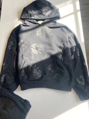 Denim Tears Cotton Wreath-Black Tracksuit - Hej 👋, Rasmus här. Säljer dessa denim tears kläder eftersom att dessa inte används av sonen.  Riktigt fina kläder och mycket bra skick (Obs, hoodien är inte blekt jag tog bara bilden i solen. 👌Perfekt för dig med bra stil. Kolla gärna mitt konto om bara ett plagg sökes.         Först till kvarn som man säger 😁✅ 