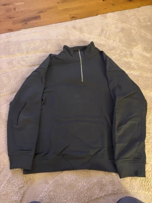 Mörkblå halfzip hoodie - En stilren mörkblå hoodie med halv dragkedja och hög krage. Tröjan har långa ärmar, ribbade muddar och är tillverkad i mjukt material. Perfekt för en avslappnad och trendig look. Från lager 157