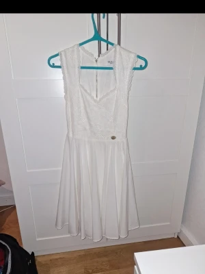 Vit spetsklänning med v-ringning  - Snygg vit klänning från Bubbleroom med v-ringning och spetsdetaljer upptill. Klänningen är ärmlös och har en lätt utställd kjol i mjukt tyg. Dragkedja bak för enkel påklädning. Perfekt för somriga tillfällen eller student. Haft när jag gick ut nian och studenten. Märket är Chiara Forthi