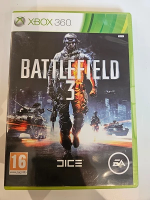 Battlefield 3 till Xbox 360 - Battlefield 3 till Xbox 360 är ett actionfyllt FPS-spel från DICE och EA. Omslaget är svart med en soldat i centrum, omgiven av stridsvagnar och explosioner. Spelet har PEGI 16-märkning och levereras i ett grönt plastfodral. Perfekt för dig som gillar intensiva multiplayerspel.